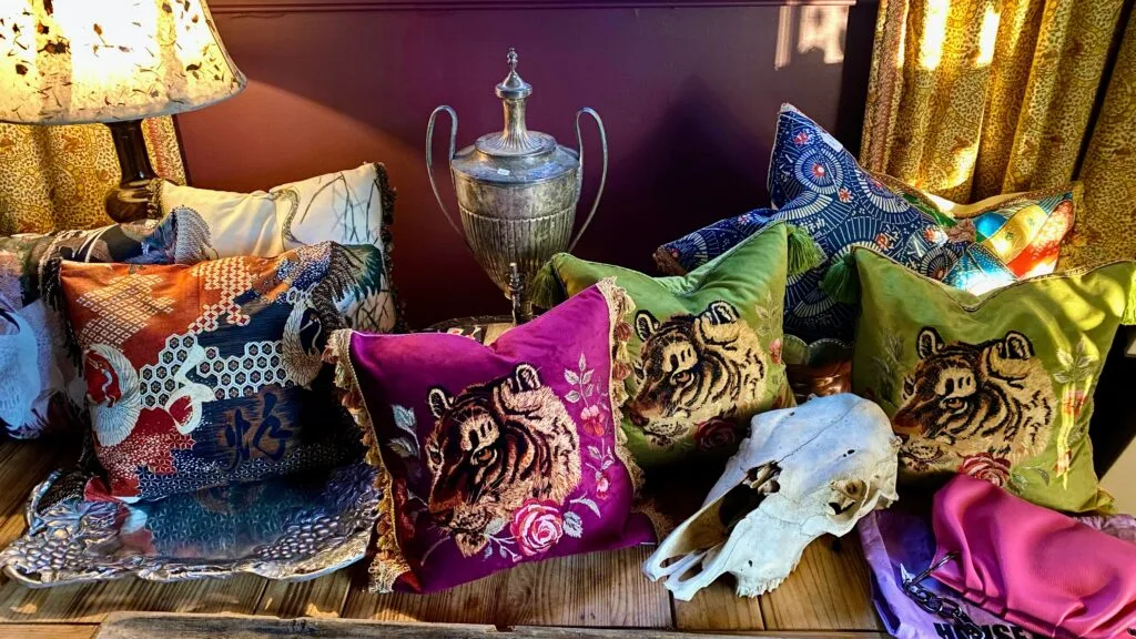 Expert pattern-mixing layout featuring custom velvet tiger pillows on a styled table.